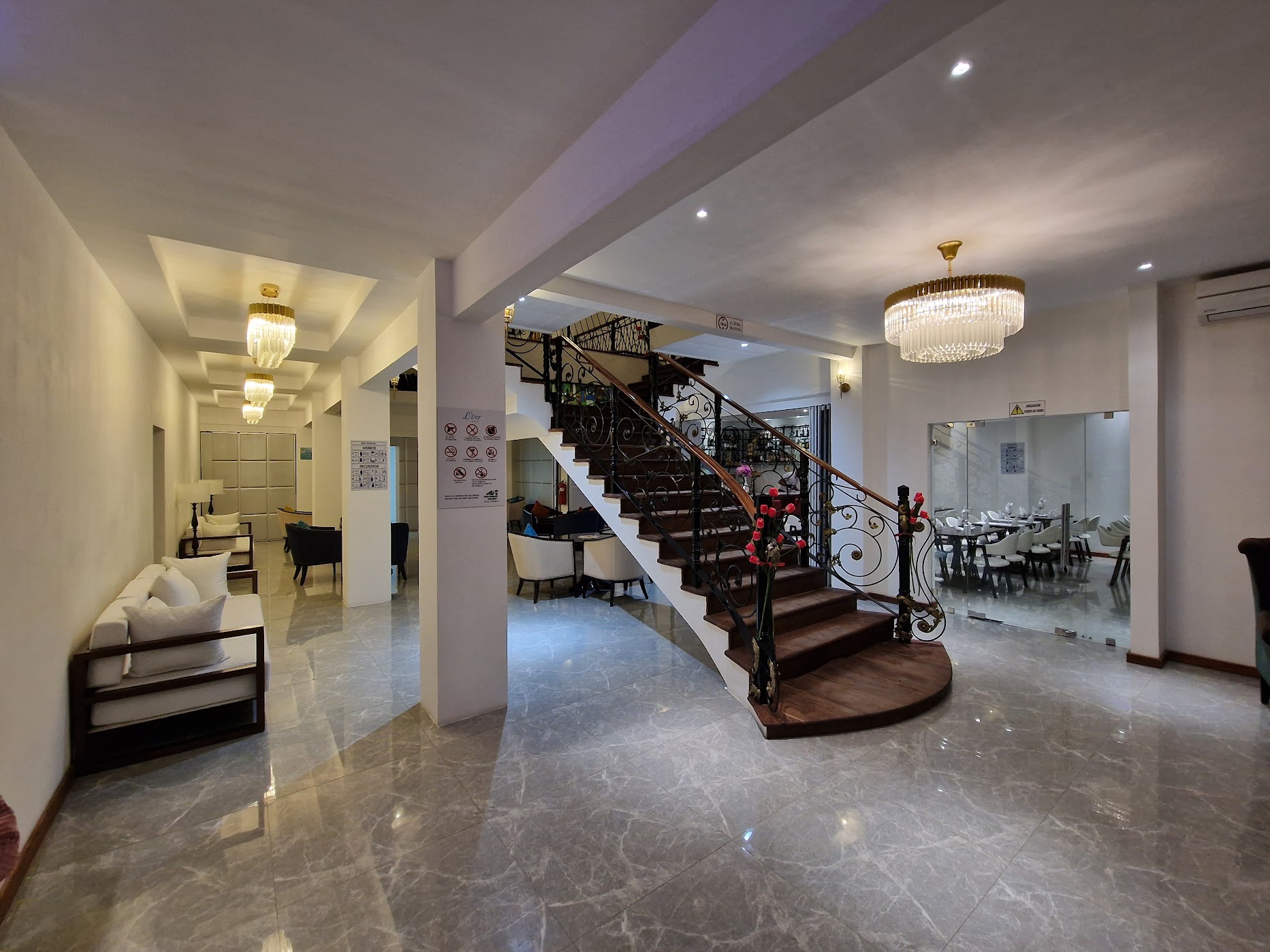 Grand lobby with iron-railed staircase and crystal chandeliers at L'ver Hotel, Somoto